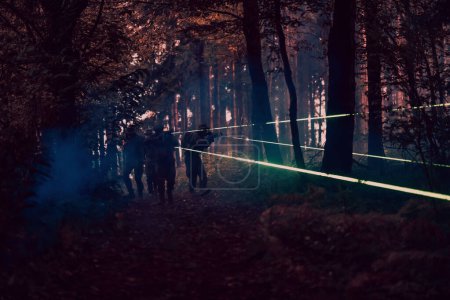 Téléchargez les photos : Escouade de soldats en action sur la mission de nuit en utilisant les feux de visée laser concept d'équipe militaire. - en image libre de droit