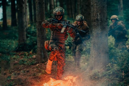 Foto de Soldado en acción por la noche en la zona forestal. Misión militar nocturna saltando sobre el fuego. - Imagen libre de derechos