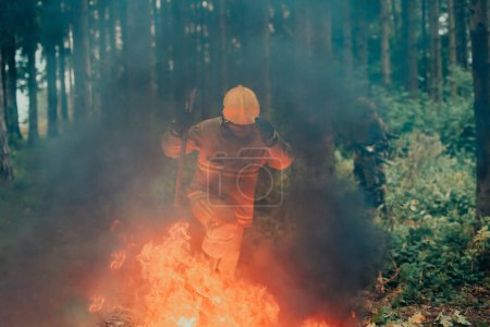 Téléchargez les photos : Héros pompier en action danger sauter par-dessus la flamme de feu pour sauver et sauver. - en image libre de droit