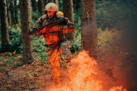 Téléchargez les photos : Soldat en action la nuit dans la région forestière. Mission militaire de nuit sautant par-dessus le feu. - en image libre de droit