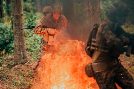 Téléchargez les photos : Soldat en action la nuit dans la région forestière. Mission militaire de nuit sautant par-dessus le feu. - en image libre de droit