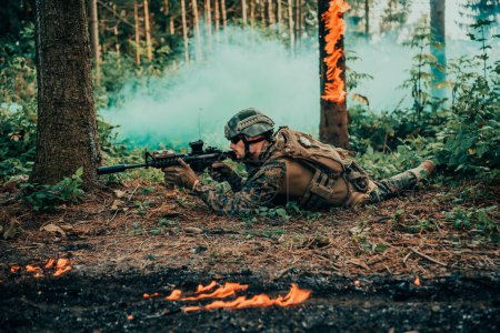 Téléchargez les photos : Soldat de guerre moderne entouré de feu, combat dans des zones forestières denses et dangereuses. - en image libre de droit