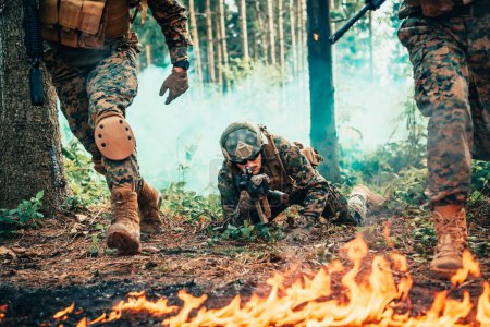 Téléchargez les photos : Soldats de guerre modernes entourés de combats de feu dans des zones forestières denses et dangereuses. - en image libre de droit