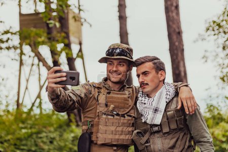 Foto de Equipo de soldados y terroristas tomando selfie con smartphone en el bosque. - Imagen libre de derechos