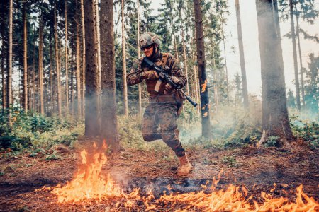 Foto de Soldado de guerra moderno rodeado de fuego, lucha en zonas boscosas densas y peligrosas. - Imagen libre de derechos
