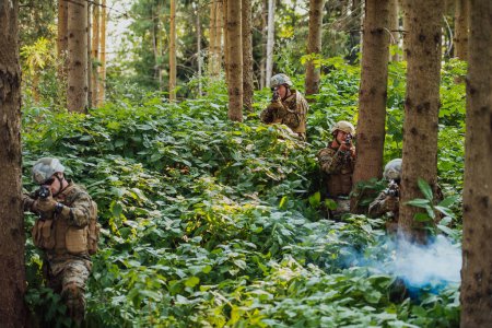 Foto de Un grupo de soldados de guerra modernos está librando una guerra en zonas forestales remotas y peligrosas. Un grupo de soldados está luchando en la línea enemiga con armas modernas. El concepto de guerra y militar - Imagen libre de derechos