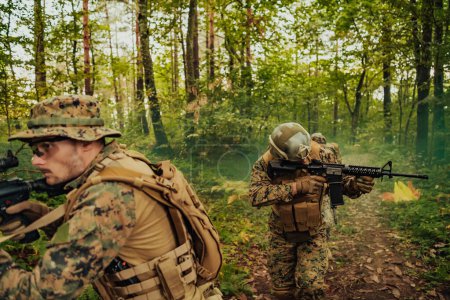 Photo for A group of modern warfare soldiers is fighting a war in dangerous remote forest areas. A group of soldiers is fighting on the enemy line with modern weapons. The concept of warfare and military - Royalty Free Image