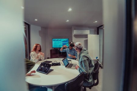 Foto de Un grupo diverso de empresarios colabora y prueba una nueva tecnología de realidad virtual, con gafas virtuales, mostrando innovación y creatividad en su espacio de trabajo futurista. - Imagen libre de derechos