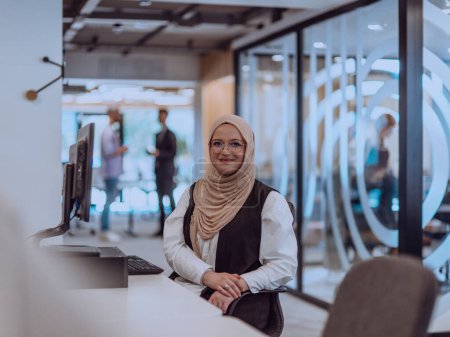 Foto de En una oficina moderna, una joven empresaria musulmana que usa un hiyab se sienta con confianza y trabaja diligentemente en su computadora, encarnando determinación, creatividad y empoderamiento en el mundo de los negocios. - Imagen libre de derechos