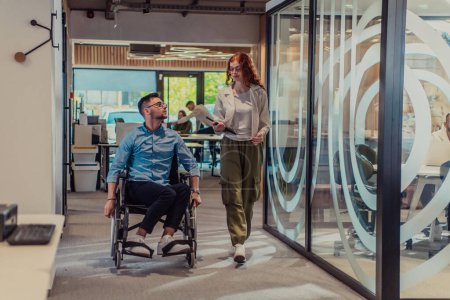 Photo for Young business colleagues, collaborative business colleagues, including a person in a wheelchair, walk past a modern glass office corridor, illustrating diversity, teamwork and empowerment in the - Royalty Free Image