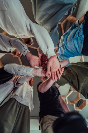 Foto de Un grupo de jóvenes empresarios ofrecen sus manos juntas, simbolizando la unión en el mundo de los negocios. - Imagen libre de derechos