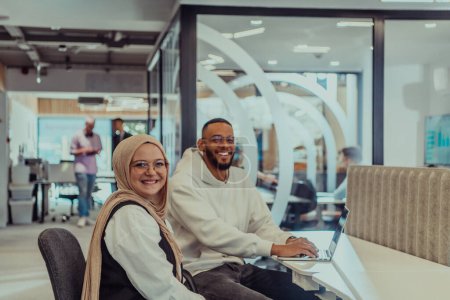 Téléchargez les photos : Dans un bureau moderne, un homme d'affaires afro-américain et son collègue musulman, portant un hijab, s'engagent dans des discussions collaboratives, abordent diverses tâches commerciales et résolvent des problèmes. - en image libre de droit