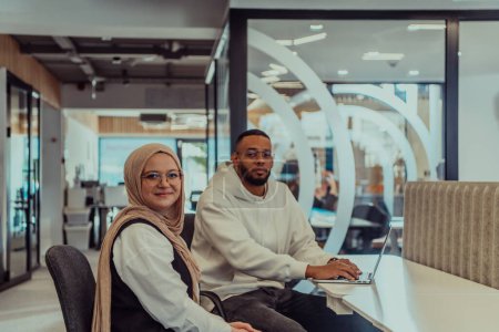Photo for In a modern office setting, an African American businessman and his Muslim colleague, wearing a hijab, engage in collaborative discussions, tackling various business tasks and solving problems - Royalty Free Image