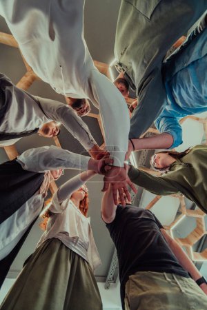 Foto de Un grupo de jóvenes empresarios ofrecen sus manos juntas, simbolizando la unión en el mundo de los negocios. - Imagen libre de derechos