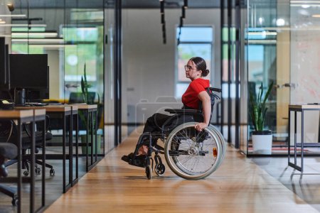 Téléchargez les photos : Une jeune femme d'affaires moderne en fauteuil roulant est entourée d'un espace de travail inclusif avec des bureaux vitrés, incarnant la détermination et l'innovation dans le monde des affaires. - en image libre de droit