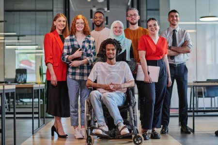 Photo for A diverse group of young business people congregates within a modern startups glass-enclosed office, featuring inclusivity with a person in a wheelchair, an African American young man , and a hijab - Royalty Free Image