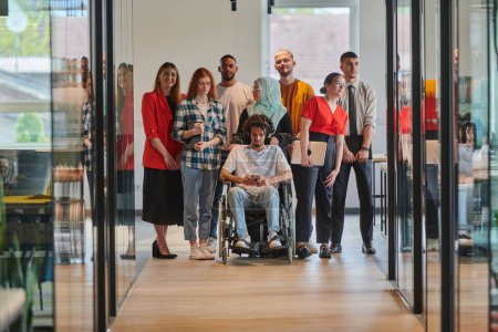 Photo for A diverse group of young business people walking a corridor in the glass-enclosed office of a modern startup, including a person in a wheelchair and a woman wearing a hijab, showing a dynamic mix of - Royalty Free Image
