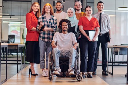Photo for A diverse group of young business people congregates within a modern startups glass-enclosed office, featuring inclusivity with a person in a wheelchair, an African American young man , and a hijab - Royalty Free Image