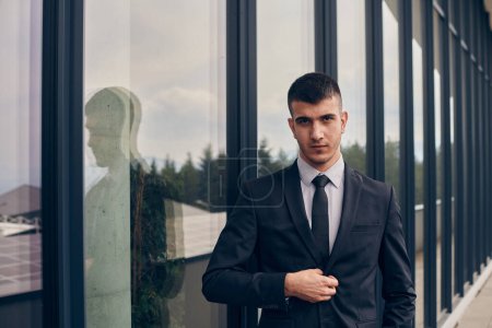 Photo for A CEO dressed in a sleek black suit stands confidently at the entrance of a modern corporate building, awaiting the start of the workday in the bustling urban environment - Royalty Free Image