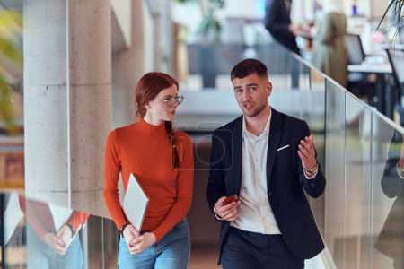 Photo for In the dynamic environment of a modern startup company, the director engages in a discussion with his young business colleague while they walk, reflecting the spirit of collaboration and innovation in - Royalty Free Image