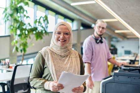 Téléchargez les photos : Dans un bureau de start-up moderne, une musulmane d'esprit d'entreprise portant un hijab collabore avec son collègue, symbolisant la diversité, l'autonomisation et le succès dans le monde contemporain des entreprises. - en image libre de droit