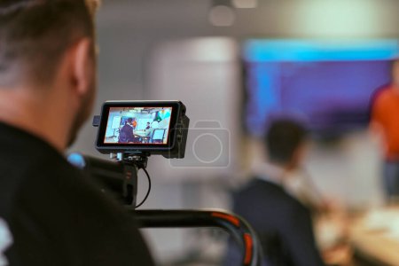 Foto de Un camarógrafo filma a un director dirigiendo una reunión en una moderna oficina de startups. - Imagen libre de derechos