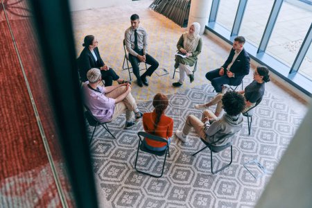 Photo for Top view of a diverse group of young business entrepreneurs gathered in a circle for a meeting, discussing corporate challenges and innovative solutions within the modern confines of a large - Royalty Free Image