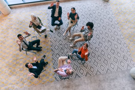 Photo for Top view of a diverse group of young business entrepreneurs gathered in a circle for a meeting, discussing corporate challenges and innovative solutions within the modern confines of a large - Royalty Free Image