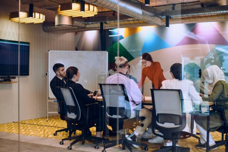 Téléchargez les photos : Une équipe diversifiée d'experts dans un bureau de verre moderne, à l'écoute attentive d'une présentation de collègues, favorisant la collaboration et l'innovation - en image libre de droit