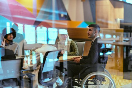 Photo for In a modern glass startup office, a wheelchair-bound director leads a successful meeting with colleagues, embodying inclusivity and teamwork - Royalty Free Image