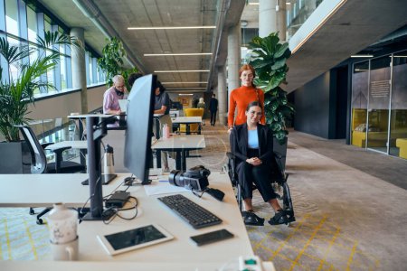 Photo for In the contemporary ambiance of a modern startup office, a compassionate businesswoman extends a helping hand to her colleague in a wheelchair, symbolizing inclusivity, teamwork, and the supportive - Royalty Free Image