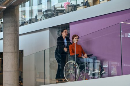 Téléchargez les photos : Dans l'ambiance contemporaine d'un bureau de démarrage moderne, une femme d'affaires compatissante tend la main à son collègue en fauteuil roulant, symbolisant l'inclusivité, le travail d'équipe et le soutien - en image libre de droit