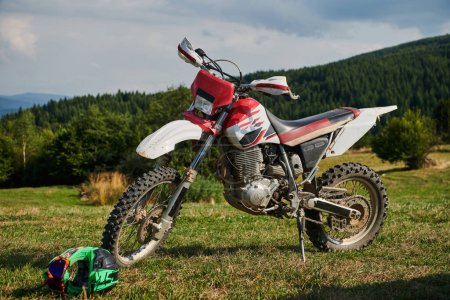 Photo for A professional motocross standing poised in a meadow, fully geared up and ready for a competitive race, with the anticipation of adrenaline-fueled excitement in the air - Royalty Free Image