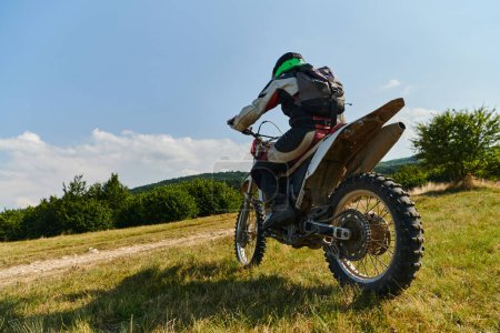 Photo for A motorcyclist equipped with professional gear, rides motocross on perilous meadows, training for an upcoming competition - Royalty Free Image