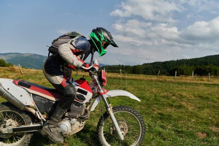 Foto de Un motociclista equipado con equipo profesional, monta motocross en prados peligrosos, entrenando para una próxima competencia - Imagen libre de derechos