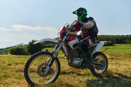 Foto de Un motociclista equipado con equipo profesional, monta motocross en prados peligrosos, entrenando para una próxima competencia - Imagen libre de derechos