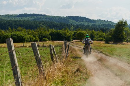 Foto de Un ciclista profesional de motocross montando un emocionante sendero forestal todoterreno traicionero en su motocicleta - Imagen libre de derechos