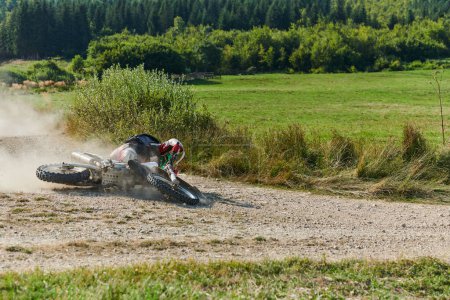 Photo for A professional motocross rider experiences an unfortunate fall from their motorcycle on a forest trail, highlighting the dangers of off-road racing - Royalty Free Image