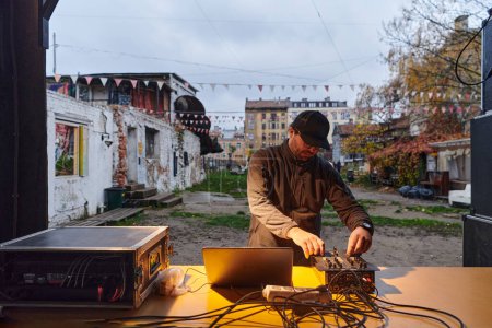 Foto de Un joven está entreteniendo a un grupo de amigos en el patio trasero de su casa, convirtiéndose en su DJ y tocando música en una reunión casual al aire libre. - Imagen libre de derechos