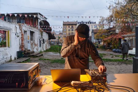 Photo for A young man is entertaining a group of friends in the backyard of his house, becoming their DJ and playing music in a casual outdoor gathering. - Royalty Free Image