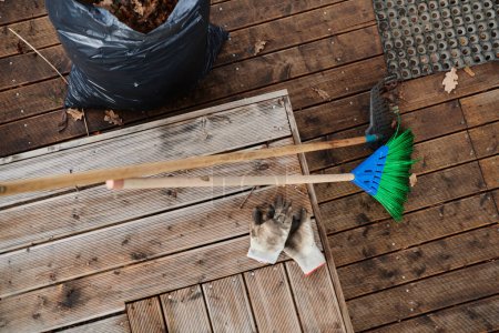 Foto de Una vista aérea captura un conjunto de herramientas de mantenimiento del jardín, que incluyen una escoba, un cubo, un rastrillo y una pala, esenciales para atender el jardín y las tareas al aire libre.. - Imagen libre de derechos