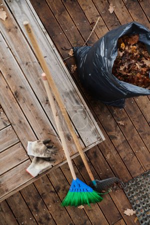 Foto de Una vista aérea captura un conjunto de herramientas de mantenimiento del jardín, que incluyen una escoba, un cubo, un rastrillo y una pala, esenciales para atender el jardín y las tareas al aire libre.. - Imagen libre de derechos