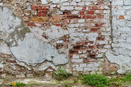 Téléchargez les photos : Un mur de briques de pierre vieilli et altéré, montrant des signes de pourriture et d'histoire, témoigne du temps et de l'usure.. - en image libre de droit