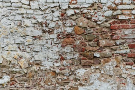 Téléchargez les photos : Un mur de briques de pierre vieilli et altéré, montrant des signes de pourriture et d'histoire, témoigne du temps et de l'usure.. - en image libre de droit