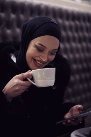 Foto de Mujeres árabes con abaya vinculación y divertirse al aire libre - Feliz Oriente Medio hembra tener un descanso tomar una taza de té en el restaurante - Imagen libre de derechos
