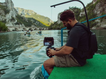 Téléchargez les photos : Un vidéaste enregistrant un groupe d'amis faisant du kayak ensemble et explorant des canyons fluviaux. - en image libre de droit