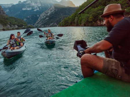 Foto de Un videógrafo grabando a un grupo de amigos haciendo kayak juntos y explorando cañones fluviales. - Imagen libre de derechos