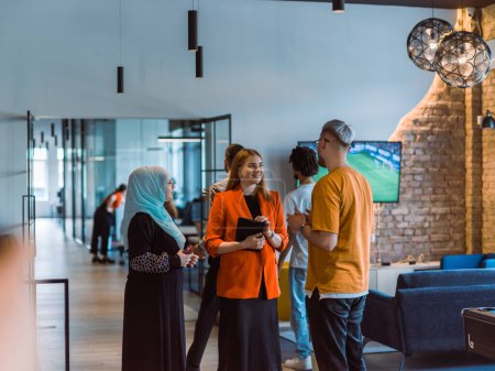 Téléchargez les photos : Un groupe de jeunes collègues d'affaires, dont une femme dans un hijab, se tient uni dans le couloir moderne d'un centre de coworking de start-up spacieux, représentant la diversité et l'esprit de collaboration. - en image libre de droit