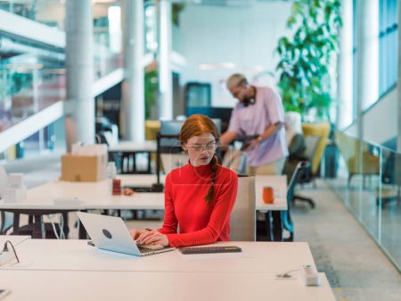 Photo for In a modern startup office, a professional businesswoman with orange hair sitting at her laptop, epitomizing innovation and productivity in her contemporary workspace. - Royalty Free Image