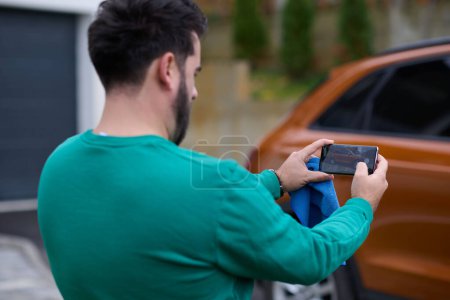 Téléchargez les photos : Homme prenant des photos sur un smartphone d'une voiture se préparant à la vente sur le marché du site en ligne - en image libre de droit